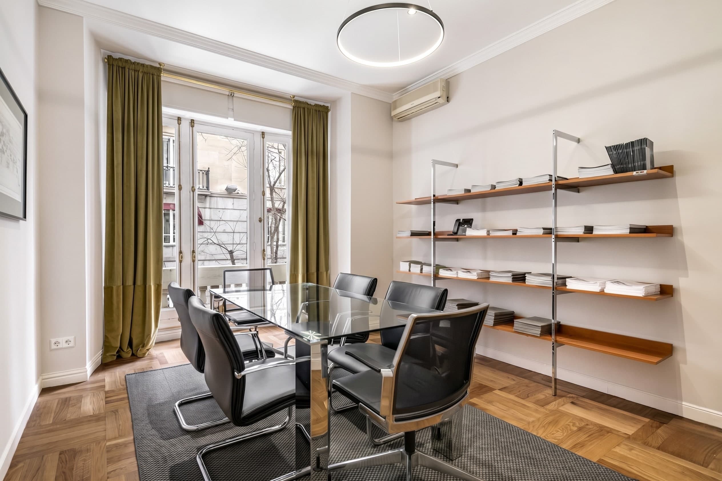 Sala de reuniones del despacho en Velázquez 10, con mesa de cristal y balcón a la calle